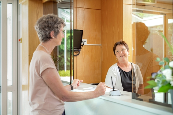 Eine Patientin wird von einer Mitarbeiterin der Klinik am Empfang begrüßt. Eine Patientin wird von einer Mitarbeiterin der Klinik am Empfang begrüßt.
