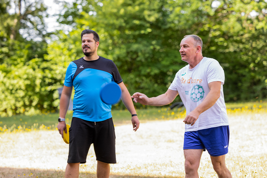 Ein Therapeut und ein Patient spielen Frisbee im Park.