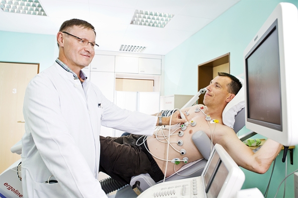 Ein Arzt führt einen Ultraschall des Herzens mit EKG an einem Patienten durch.